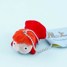 a small red stuffed animal with a chain around it's neck and earring