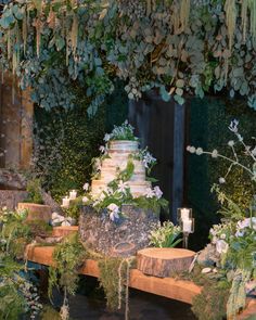 a wedding cake sitting on top of a wooden table surrounded by greenery