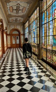 a woman is walking down the hall in front of stained glass windows and flooring