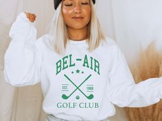 Bel-Air Golf Club Sweatshirt Preppy Golf Sweatshirt Golfing Unisex Sweater Vintage California Golf Sweater Golf Gifts Please allow 3-5 days for processing plus 3-5 days for shipping Ideal for any situation, a unisex heavy blend crewneck sweatshirt is pure comfort. This sweatshirt is made from polyester and cotton. This combination helps designs come out looking fresh and beautiful. The collar is ribbed knit, so it retains its shape even after washing. There are no itchy side seams on these sweat White Collegiate Golf Tops, Collegiate White Top For Golf, White Collegiate Style Tops For Golf, Sporty Letter Print Sweatshirt For Golf, Sporty Crew Neck Golf Sweatshirt, Sporty Crew Neck Sweatshirt For Golf, Sporty Long Sleeve Sweatshirt For Golf, Cat Mom Sweater, Cat Mom Sweatshirt