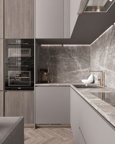 a modern kitchen with marble counter tops and grey cupboards, along with an oven