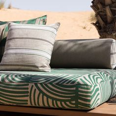 a couch sitting on top of a wooden table next to a palm leaf covered wall