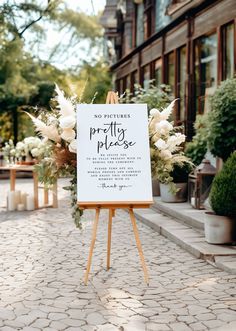 an easel with a sign that says no pictures, pretty please and flowers on it