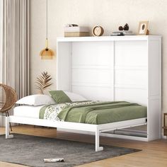 a white bed sitting next to a window in a room with wooden floors and furniture