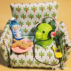 a green toy sitting on top of a chair next to a bottle and headphones