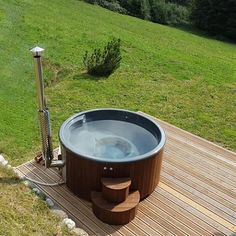 a hot tub sitting on top of a wooden deck next to a lush green field