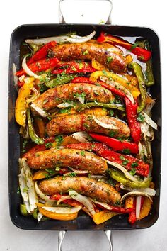 a pan filled with sausages, peppers and onions