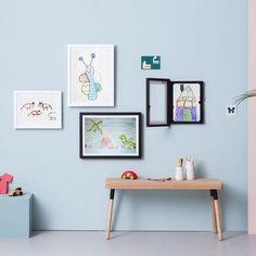 a blue wall with pictures on it and a wooden bench in front of the table