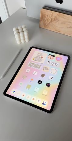 an ipad sitting on top of a desk next to a wooden block and some pens