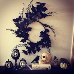 a halloween decoration with bats and skulls on a shelf in front of a white wall