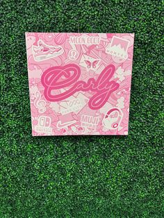 a pink sign that is on top of a green grass covered wall with the word girl