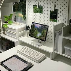 a desk with a computer monitor, keyboard and tablet