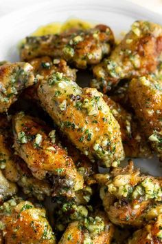 chicken wings covered in herbs on a white plate