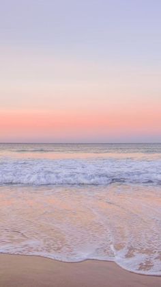 two people walking on the beach at sunset