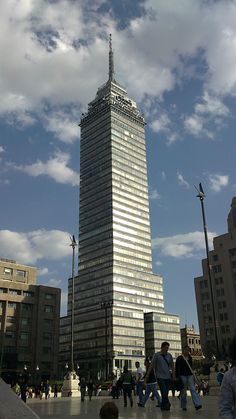 people are walking around in front of a tall building