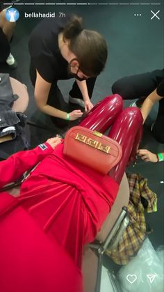 a woman in a red dress is sitting on a chair with her legs spread out