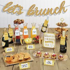 a wooden table topped with lots of desserts and bottles of wine on top of it