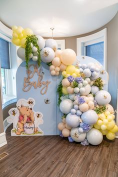 an arch made out of balloons and greenery is decorated with winnie the pooh