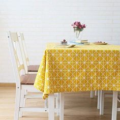 a yellow table cloth with white chairs around it