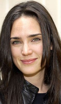 a close up of a person wearing a leather jacket and smiling at the camera with long hair