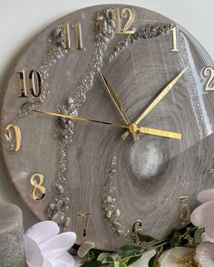 a clock that is sitting on a table with flowers and beads around the clock face