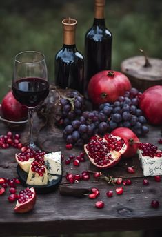 a table topped with wine, cheese and pomegranates