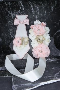 a bouquet of flowers sitting on top of a black marble table next to a white ribbon