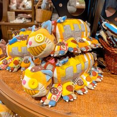 several stuffed animals are sitting on a table with other items in the background and baskets behind them