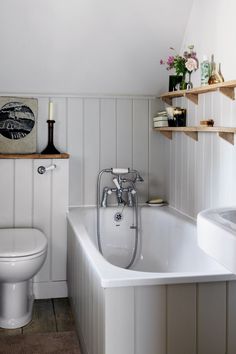 a bathroom with a toilet, tub and shelves on the wall next to the bathtub