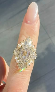 a woman's finger with a ring on it that has diamonds and pearls in the middle