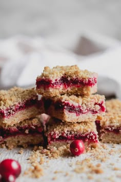 cranberry bars stacked on top of each other with cranberries scattered around them