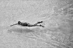 black and white photo of a person swimming in the water