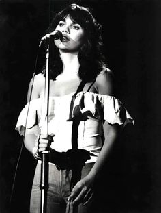 a black and white photo of a woman singing into a microphone