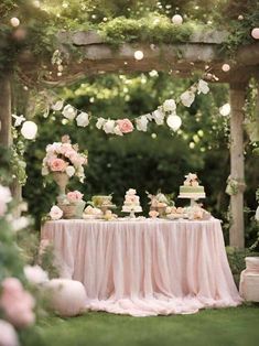 a table with cake and flowers on it in the middle of a lush green garden