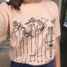 a woman wearing a pink t - shirt with musical instruments on it's chest