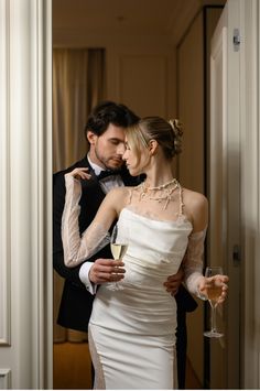 the bride and groom are posing for a photo in their wedding dress, holding champagne glasses