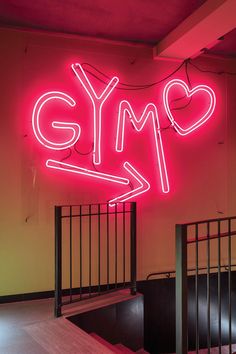 a large neon sign that says gym on the side of a wall next to stairs