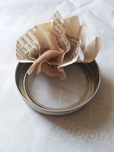 a close up of a metal ring with some paper on it and a flower in the middle