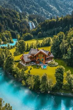 an aerial view of a large house in the middle of a forest with a river running through it