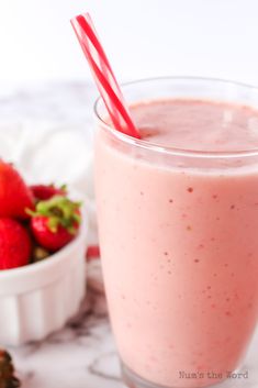 a smoothie in a glass with strawberries next to it