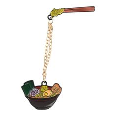 a bowl with chopsticks and vegetables hanging from it's side on a chain