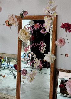 a mirror with flowers hanging from it's sides and the words spring is here