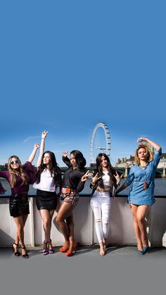 four beautiful young women standing next to each other in front of the london eye chart