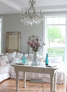 a living room filled with furniture and a chandelier hanging from the ceiling over a white couch