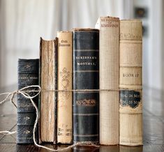 several old books sitting on top of a wooden table with twine tied around them