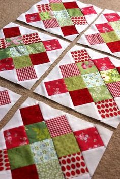 four red and green patchwork quilts laid out on the floor with one block missing