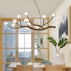 a dining room table and chairs with lights hanging from the ceiling