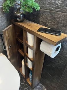 a bathroom with toilet paper and a plant on the shelf next to it, as well as a roll of toilet paper