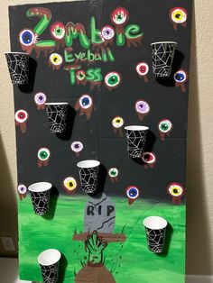 this is a cardboard board with cups on it and the words zombie eyeball toss