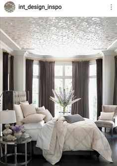 a bed room with a neatly made bed next to two chairs and a large window